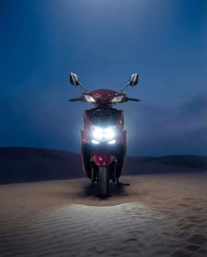 EVE E05 electric scooter with headlights on in the desert at night